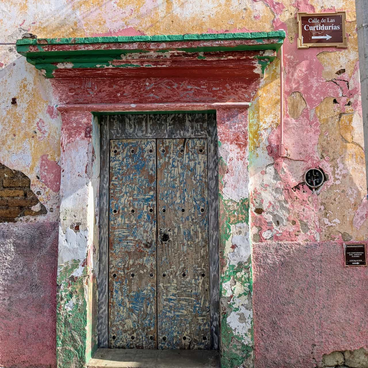 A wall and door painted with red, green, and white but distressed so the colors blend.