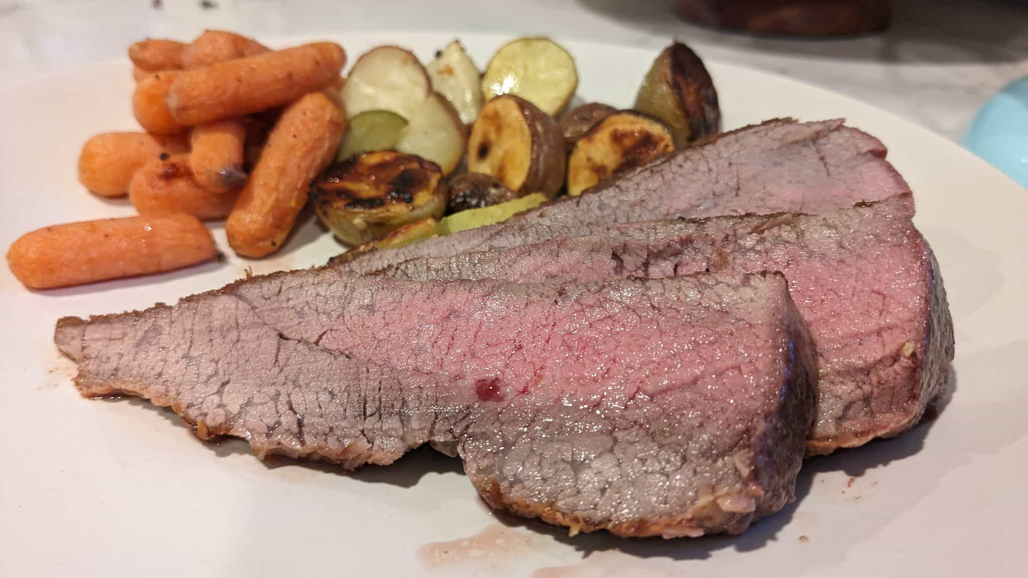 Cut steak on a plate with potatoes and carrots.