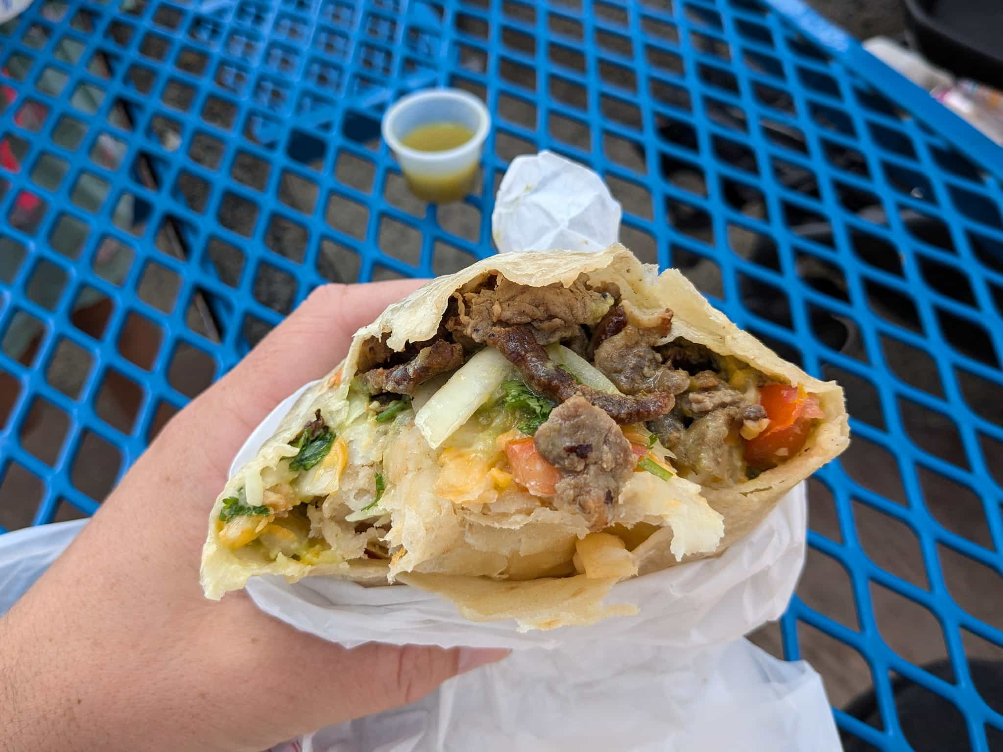 Closeup looking inside a burrito with cheese, beef, onions, and